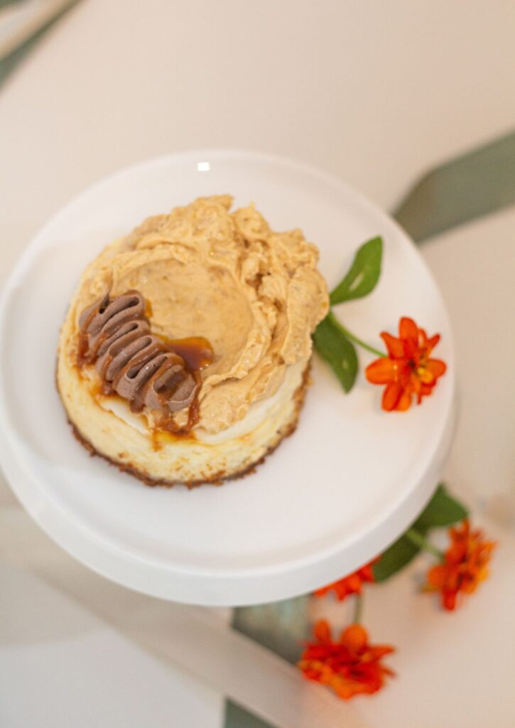 Mini Baked Cheesecake - rum caramel and pecan topping with orange flowers on white cake stand