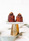 Canelé - caramelized hazelnuts and chocolate topping on gold cake stand
