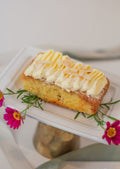 Flourless Almond Cake - golden moist cake slice with cream cheese frosting and pink daisies on white cake stand