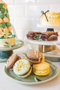 Giant Macaron Party Box - pistachio, chocolate hazelnut and lemon giant macarons on green plate with dessert table in background