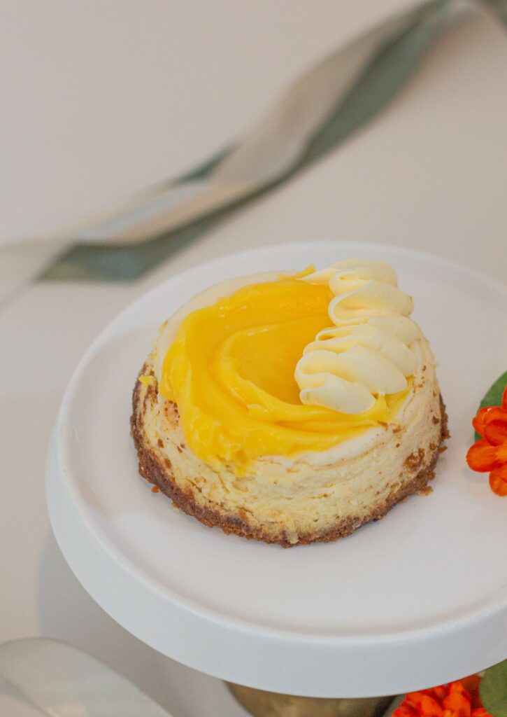 Mini Baked Cheesecake - lemon cream topping with whipped cream rosette on white cake stand