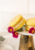 Giant Strawberry Nesquick Macaron - two golden yellow macarons with pink daisies on white gold cake stand