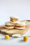 Giant Cheesecake Macarons - three stacked macarons with caramel filling on wooden board with yellow flowers